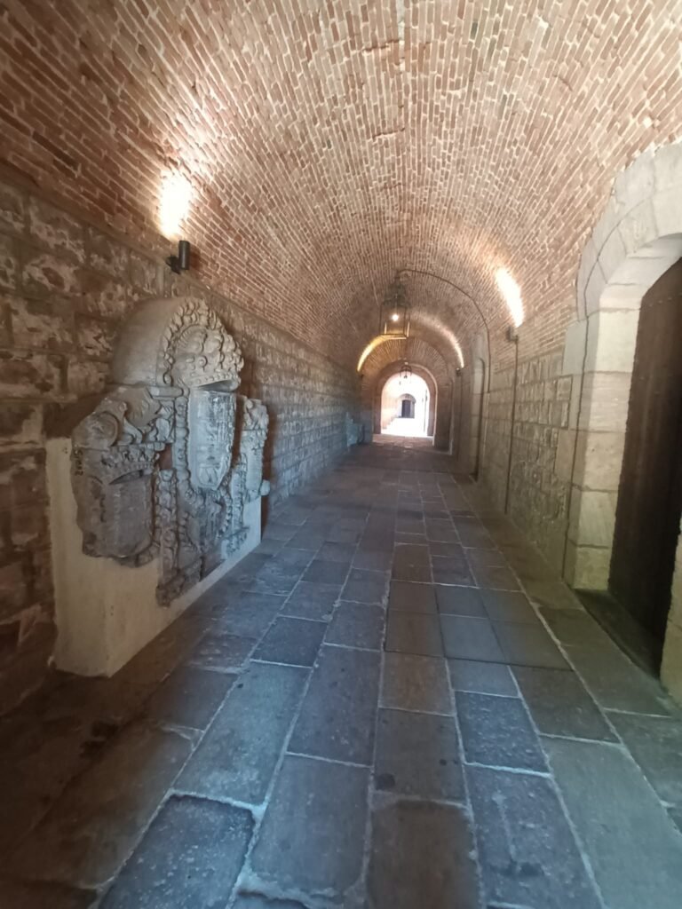 Pasillo interior del Castell de Montjuïc con forma de túnel, iluminado con faroles antiguos