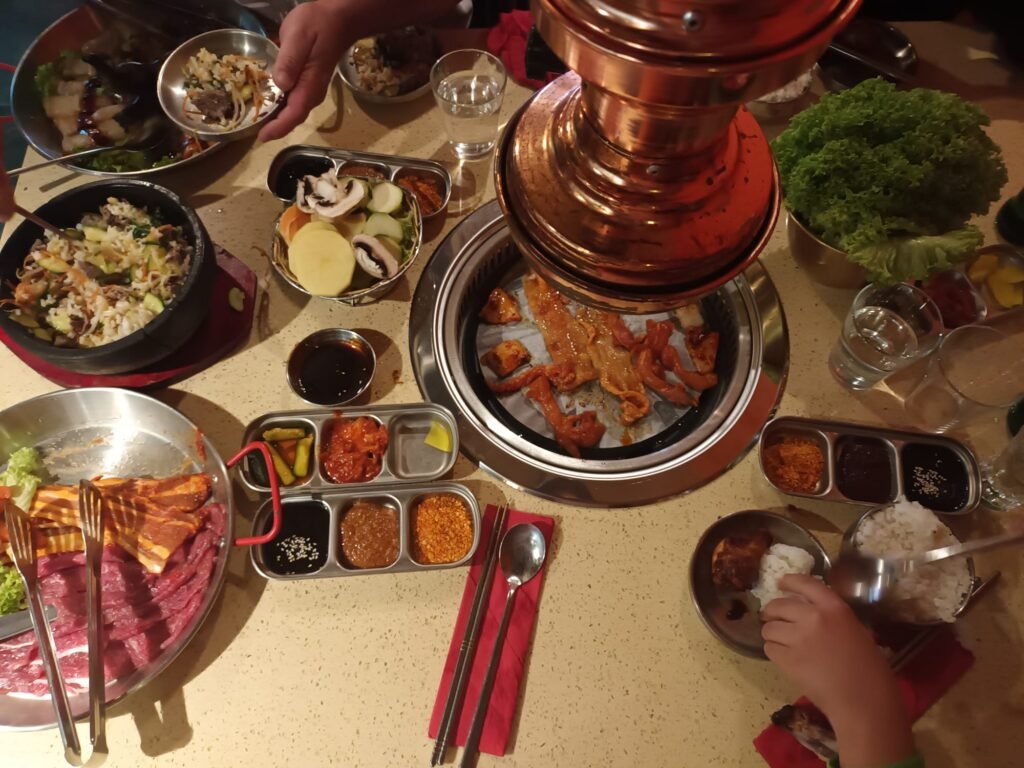 Vista completa de una comida familiar coreana en Chez Kimchi, con ingredientes listos para cocinar.